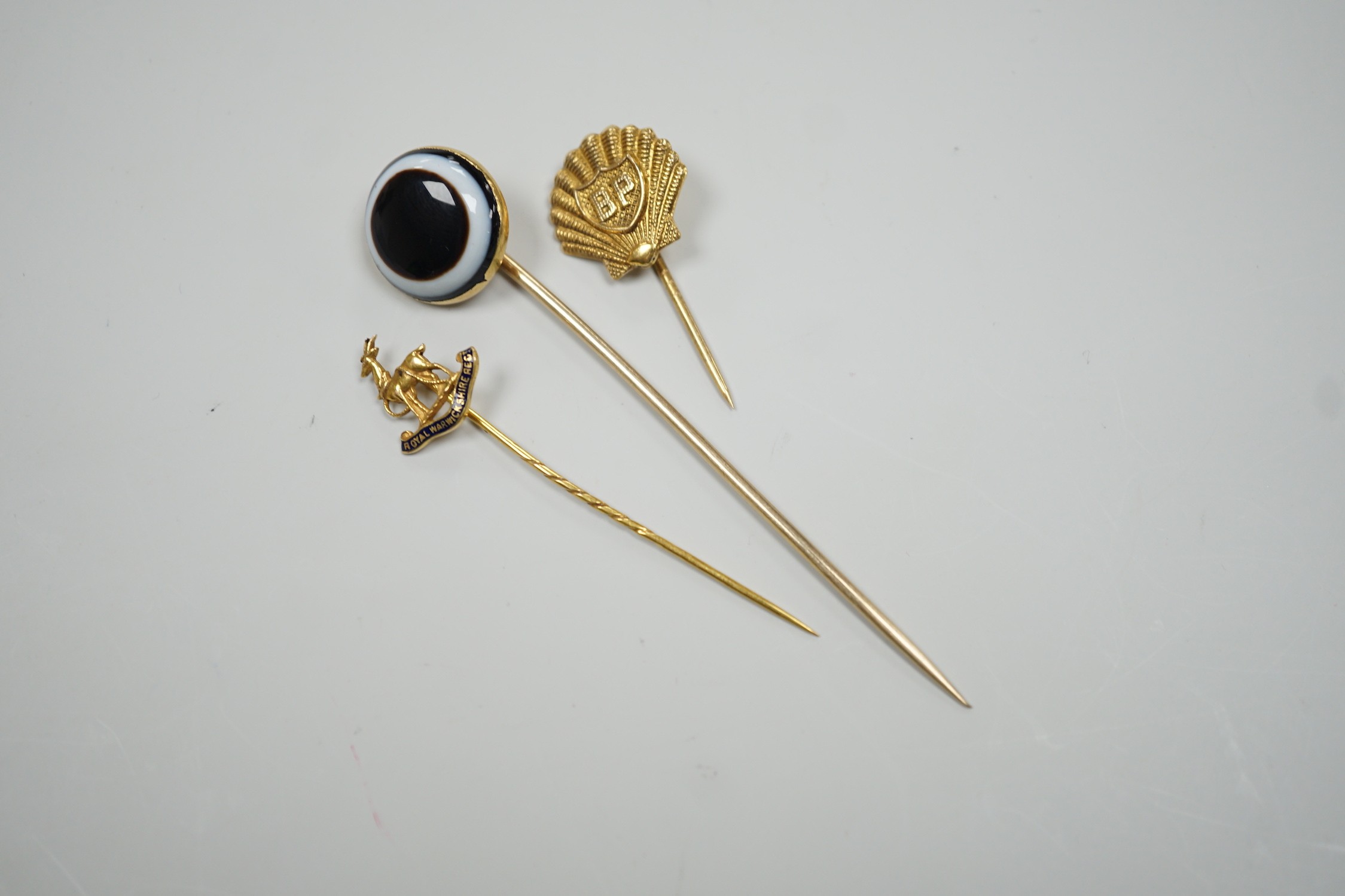 A Victorian yellow metal and banded agate set stick pin, 84mm, a yellow metal Royal Warwickshire Regt. stick pin and a 1970's 9ct gold BP stick pin, gross weight 11.5 grams.